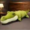 Un gros coussin en forme de crocodile vert sur un canapé.