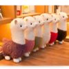 Six peluches de lama en blanc et différentes couleurs, alignées sur un rayon de librairie.