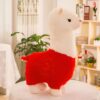 Peluche de lama blanc et rouge debout sur une table blanche.