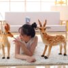 grande-peluche-cerf-jouet-peluche-animal-realiste-pour-enfant-decoration-3a-2 Une jeune femme souriante allongée sur un tapis blanc avec deux peluches de cerfs.