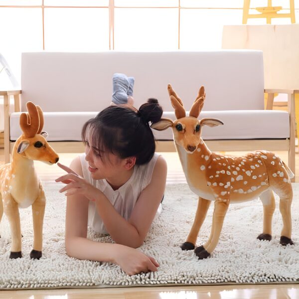 grande-peluche-cerf-jouet-peluche-animal-realiste-pour-enfant-decoration-3a-2 Une jeune femme souriante allongée sur un tapis blanc avec deux peluches de cerfs.