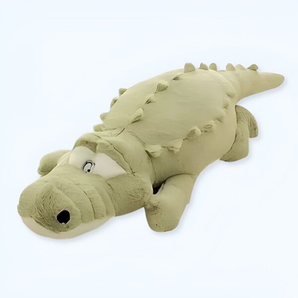 Grande peluche crocodile vert allongé sur le dos, avec des yeux noirs et une bouche ouverte.