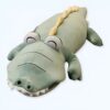 Une peluche de crocodile vert avec des yeux noirs et des dents blanches.