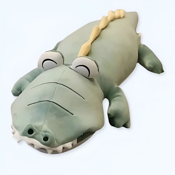 Une peluche de crocodile vert avec des yeux noirs et des dents blanches.