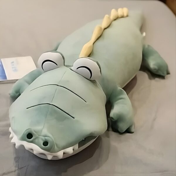Un gros crocodile en peluche vert avec des yeux noirs et une crête jaune sur le dos.