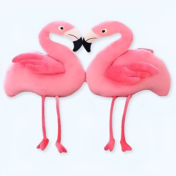 Deux flamants roses en peluche se font face, la tête contre la tête. Ils sont de couleur rose vif et ont des pattes fines et des ailes pliées.