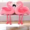 Deux adorables peluches flamants roses se tenant l'un contre l'autre sur un canapé.