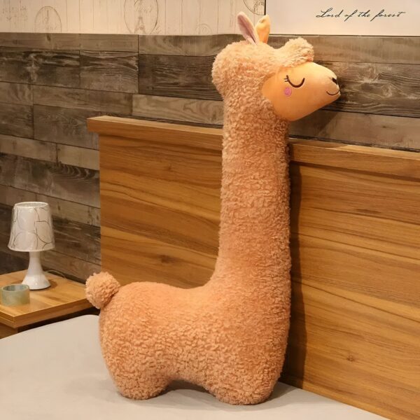 grande-peluche-lama-geante-cadeau-ideal-pour-enfants-et-adultes-1a Un oreiller en forme de lama en peluche beige sur un lit en bois.