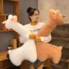 grande-peluche-lama-geante-cadeau-ideal-pour-enfants-et-adultes-4a Une jeune femme sourit en tenant deux peluches en forme d'alpaga, l'une blanche et l'autre beige.