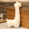 grande-peluche-lama-geante-cadeau-ideal-pour-enfants-et-adultes-6a-2 Un oreiller en forme de lama blanc moelleux posé sur un lit avec une tête de lit en bois.