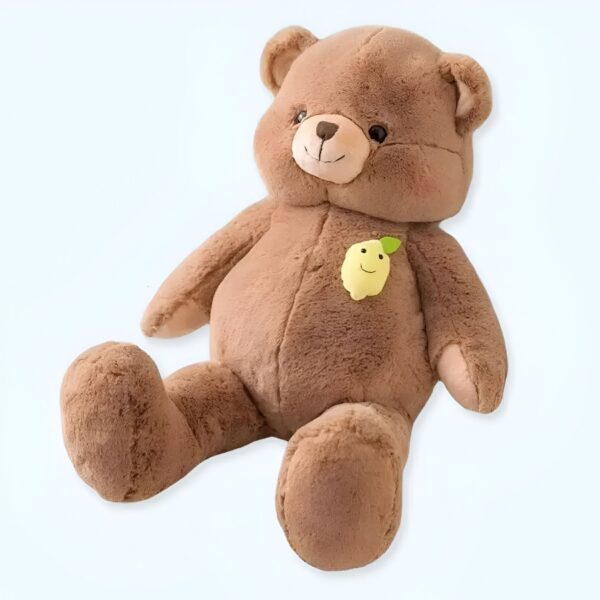 Ours en peluche brun assis avec un citron souriant sur la poitrine.