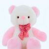 Un ours en peluche blanc avec un nœud rose à pois assis sur un fond blanc.
