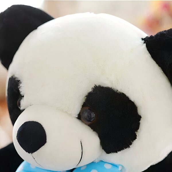 Gros plan sur la tête d'une peluche panda avec un nœud bleu à pois blancs.