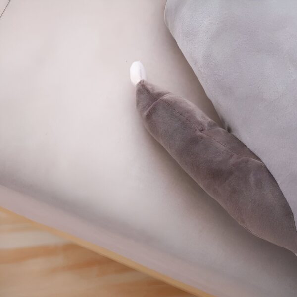 La queue d'un animal en peluche gris sur un lit blanc.
