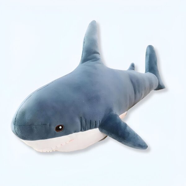 Une peluche de requin bleu foncé avec une bouche ouverte et des dents blanches.