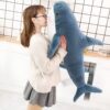 Une jeune femme tenant un grand requin en peluche bleu et blanc.