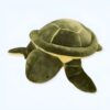 Une grande tortue en peluche verte avec une coquille en forme de dôme. Elle est posée sur un fond blanc.