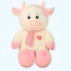 grande-peluche-vache-blanche-et-rose-70-cm-1a-2 Une peluche de vache blanche avec des taches roses, portant un foulard rose à rayures blanches et un cœur rouge brodé sur la poitrine.