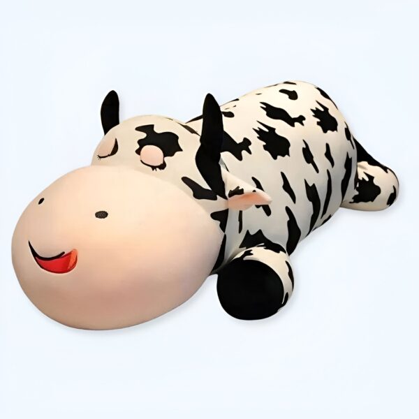 grande-peluche-vache-pour-dormir-doudou-confort-et-tranquillite-5a-1 Une peluche en forme de vache noire et blanche couchée sur le dos avec les yeux fermés et un sourire.
