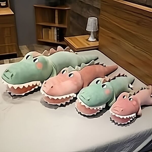 grosse-peluche-crocodile-verte-jouet-doux-pour-bebe-et-enfant-differentes-tailles-3a Quatre crocodiles en peluche en vert, rose et beige posés sur un lit blanc.