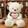 ours-en-peluche-je-t-aime-cadeau-saint-valentin-4a-4 Une grande peluche blanche tenant un cœur rose avec l'inscription "Je t'aime".