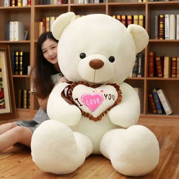 ours-en-peluche-je-t-aime-cadeau-saint-valentin-4a-4 Une grande peluche blanche tenant un cœur rose avec l'inscription "Je t'aime".