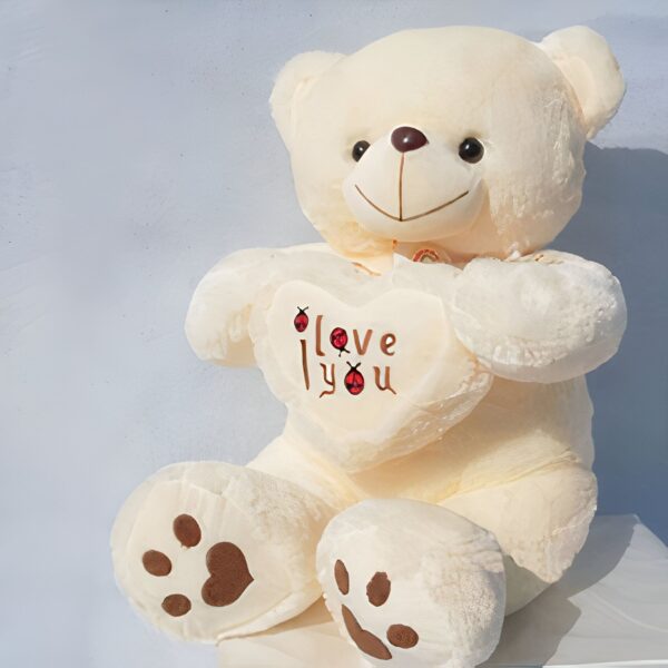 Un grand ours en peluche blanc tenant un cœur avec l'inscription "I love you".