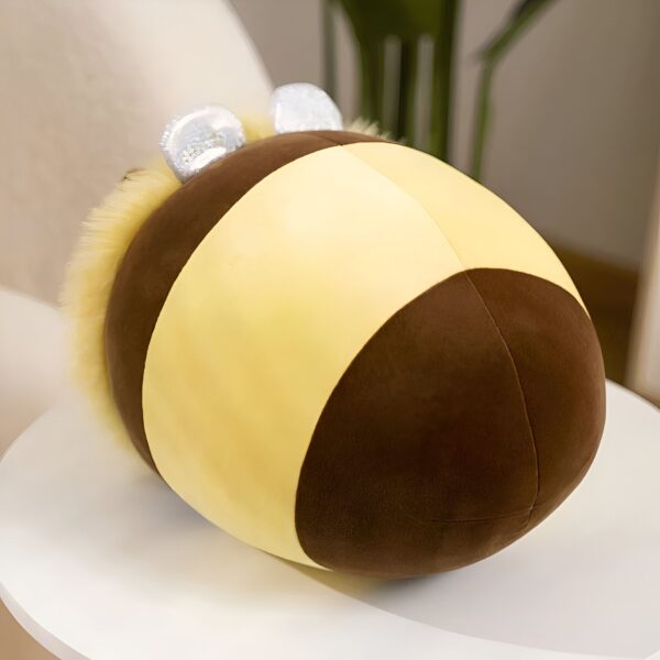 Coussin en forme d'abeille en peluche, jaune et brun, avec des ailes scintillantes.