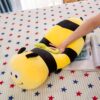 peluche-abeille-coussin-souriante-jouet-en-peluche-doux-pour-enfants-4a-2 Un gros coussin en forme d'abeille jaune et noire sur un lit avec des étoiles rouges et bleues.