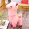 Peluche rose en forme de lama avec des détails colorés sur l'oreille et le dos.