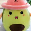 Peluche avocat souriant portant un chapeau rose.