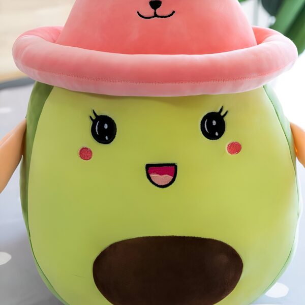 Peluche avocat souriant portant un chapeau rose.