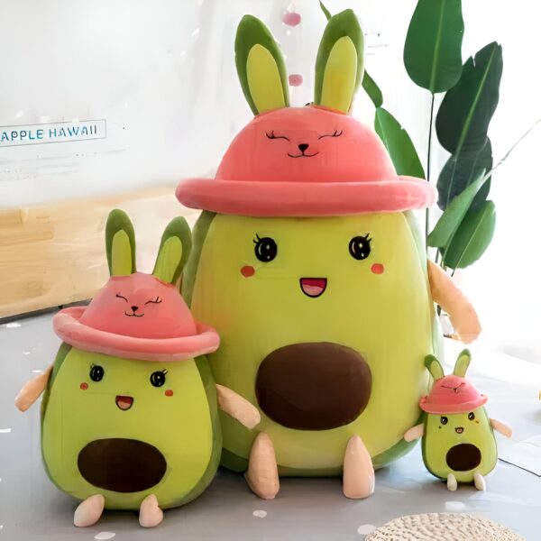 Trois peluches en forme d'avocat avec des oreilles de lapin et un chapeau rose.