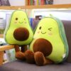 peluche-avocat-mignon-pour-fille-2a-2 Deux peluches en forme d'avocats souriants avec des joues roses et des yeux brodés. Elles sont assises sur un fauteuil en bois.