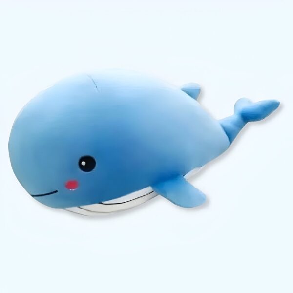 Une peluche bleue en forme de baleine avec un sourire et une petite nageoire dorsale.