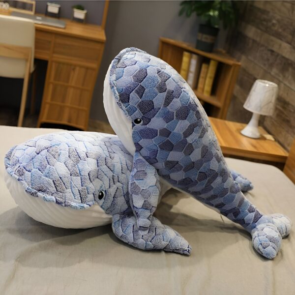 peluche-baleine-bleue-mosaique-grande-taille-jouet-en-peluche-douce-3a Deux grandes baleines en peluche bleu et blanc avec un motif géométrique. Les baleines sont posées sur un lit blanc.