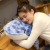 peluche-baleine-bleue-mosaique-grande-taille-jouet-en-peluche-douce-4a Une jeune femme dort enlaçant une grande peluche en forme de baleine bleue à motifs hexagonaux.