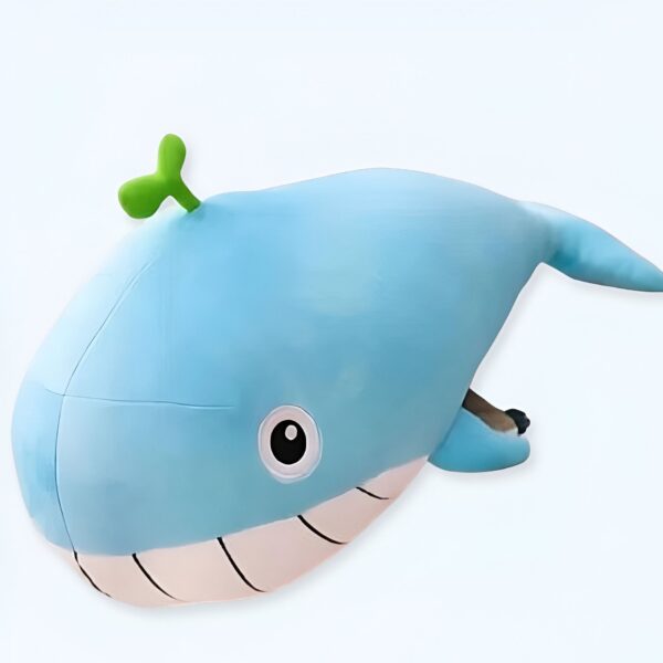 Une baleine bleue en peluche avec un petit œil noir et une feuille verte sur la tête.