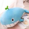 Une peluche baleine bleue avec une petite feuille verte sur la tête, posée sur une table.