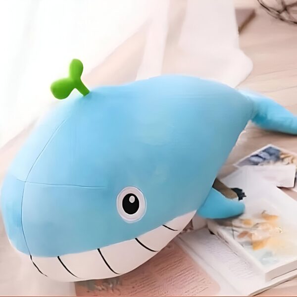 Une peluche baleine bleue avec une petite feuille verte sur la tête, posée sur une table.