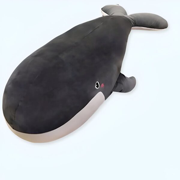 Grande peluche en forme de baleine noire avec un ventre blanc et un petit œil rose.