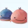 Deux peluches en forme de baleine, une bleue et une rose, avec un sourire et des joues roses.