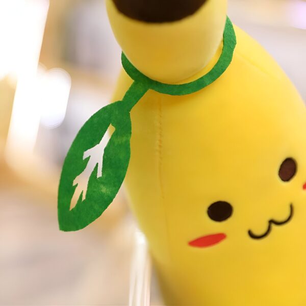Une banane en peluche jaune avec un visage souriant et une feuille verte.