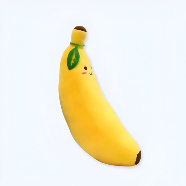 Coussin en forme de banane jaune avec une feuille verte et un visage souriant.