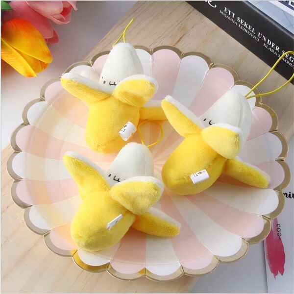 Trois peluches jaunes en forme de banane sur une assiette rose.