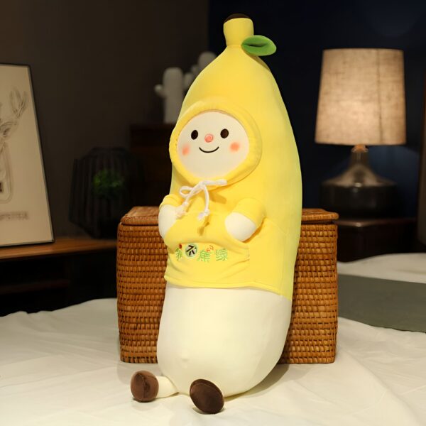 peluche-banane-kawaii-oreiller-doux-et-moelleux-2a Peluche banane souriante portant un sweat à capuche jaune.