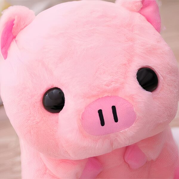 Gros plan sur la tête d'un cochon rose en peluche avec de grands yeux noirs.