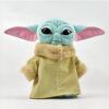 Peluche Baby Yoda portant un manteau vert avec une doublure en fausse fourrure. Il a de grands yeux noirs et des oreilles roses.