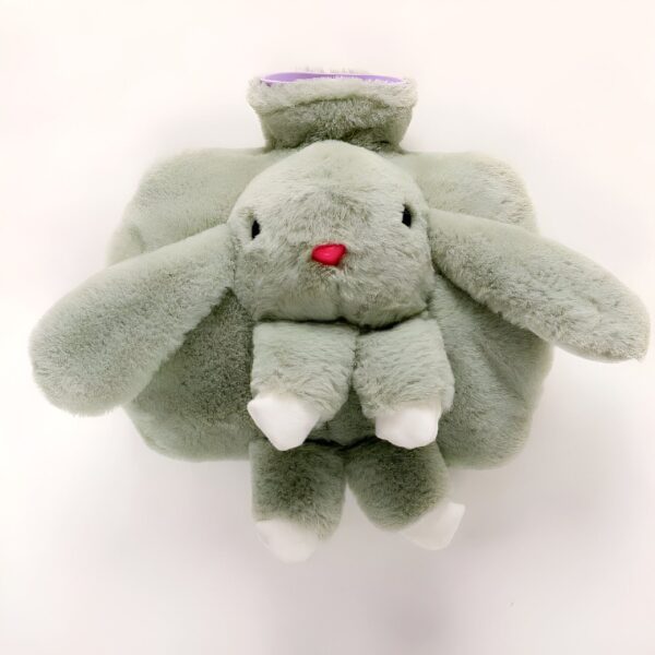 Bouillotte en forme de lapin en peluche de couleur vert clair avec un nez rouge.