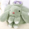 Une bouillotte en forme de lapin vert en peluche avec des oreilles longues et une bouche rose.